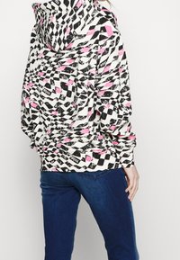 Felpa con cappuccio in un motivo geometrico nero, bianco e rosa. Realizzata in tessuto morbido, presenta polsini e orlo a costine, dettagli del logo sul retro.