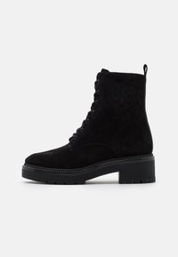 Botte de cheville en suède noir avec bout rond, devant à lacets, détails cousus, logo texturé sur le côté et semelle en caoutchouc épaisse.