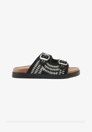 Chancla tejida negra con hebillas plateadas, plantilla de cuero marrón y suela de goma negra texturizada. Presenta un diseño abierto y casual.