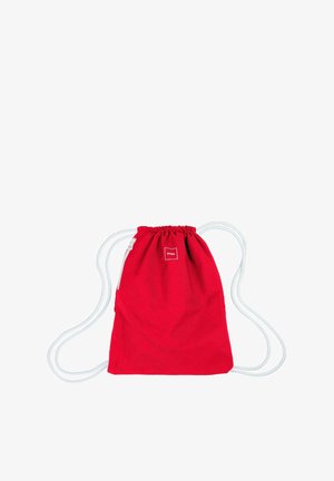 Red drawstring bag made of fabric with white cords. Features a small square logo tag near the top. Simple, functional design.