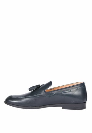 Mocassino in pelle nera con dettaglio a nappina, tacco basso e cuciture decorative lungo la parte superiore, vista laterale su sfondo bianco.