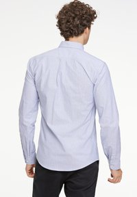 Ljusblå och vitrandig långärmad skjorta med knäppbar krage och manschettdetaljer, tillverkad av ett mjukt tyg med en skräddarsydd passform.