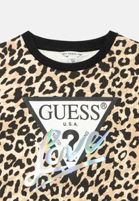 Sweatshirt à imprimé léopard avec un col ras du cou côtelé noir, un logo plastique "Guess" et un accent irisé "Love". Fabriqué en tissu doux.