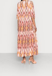 Maxiklänning med ett färgmönster i orange, pink och brunt med en diamantdesign. Lätt oversizepassform, trekvartsärmar och flerlagerssektioner.