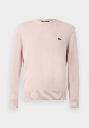 Hele roosa kudum-sviiter ribatud kaela- ja varrukate servadega. Vasakul rinnas on väike roheline Lacoste logo. Pehme tekstuur, klassikaline lõige.