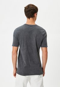 Mørkegrå bomulds t-shirt med korte ærmer. Har rund halsudskæring og en blød tekstur. Ingen synlige grafikker eller mønstre.