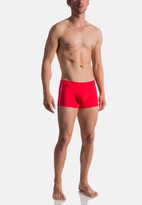 Röda badshorts med en figurnära design, elastisk midja och vita sidostråkar, tillverkade av ett slätt, elastiskt material.
