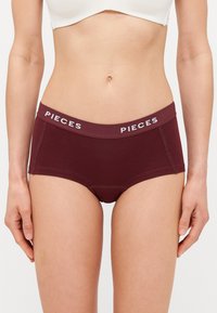 Burgundi színű pamut hipster alsónemű széles gumírozott derékkal, amelyen a "PIECES" logo található. Sima tapintású és testhezálló fazon, varrási részletekkel.
