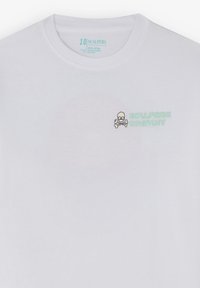 T-shirt in cotone bianco a maniche corte con piccolo logo di teschio e tibie e testo "Scalpers Company" sulla parte superiore sinistra del petto.