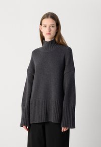 Pull en maille gris charbon avec un col haut côtelé, des manches larges et un ourlet côtelé. Texture douce, coupe décontractée et design minimaliste.