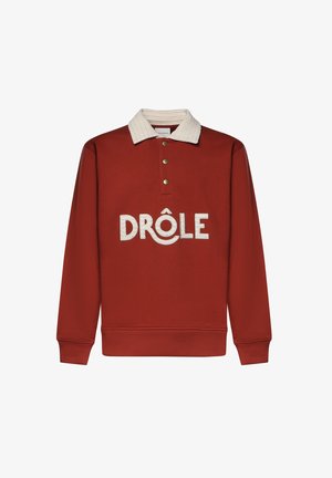 Sweat-shirt à manches longues couleur rouille avec col texturé crème, trois boutons métalliques et « DRÔLE » brodé en grandes lettres crème sur le devant.