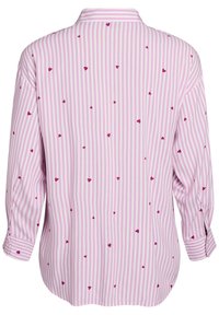 Blouse rose à manches longues avec des rayures verticales blanches et de petits motifs de cœurs rouges. Dotée d'un col pointu et de poignets boutonnés.