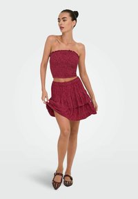 Fuchsia tweed set met een strapless crop top met gerafelde randen en een gelaagde mini rok. Geverfde stof, casual pasvorm.
