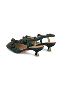 Scarpe con stampa leopardata verde, dotate di un fiocco nero testurizzato, un tacco metallico basso e una chiusura con cinturino. Silhouette classica.