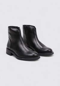 Black leather ankle boots with a side zipper, stacked heel, smooth texture, and rounded toe design. Minimalist and sleek appearance.