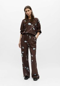 Ensemble de vêtements d'intérieur marron à motif floral comprenant un haut à manches longues et un pantalon à jambes larges, réalisé en matière texturée avec une coupe décontractée.