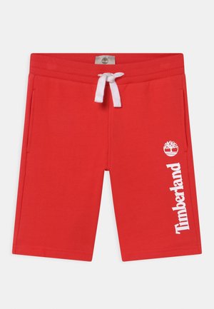 Pantalones cortos de algodón rojos con cordón blanco, bolsillos laterales y un estampado del logo de Timberland en blanco a lo largo del lado izquierdo. Presentan una etiqueta de logo en la cintura.