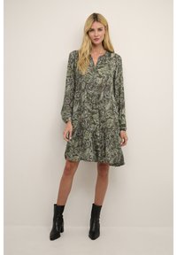 Rochie verde cu model paisley, cu mâneci lungi, decolteu în V, tiv volănat și țesătură ușoară. Asortată cu cizme negre până la glezne.