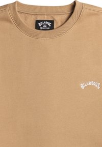 Beige sweatshirt made of soft material, featuring a crew neck, ribbed cuffs, and white embroidered "Billabong" logo on the chest.