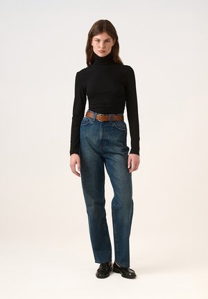 Un pulover negru cu guler înalt, blugi albaștri cu talie înaltă, o curea din piele maro și pantofi negri. Design simplu, textură netedă, croială clasică.