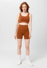 Bruine crop top en high-waisted shorts set gemaakt van rekbare stof. Het ontwerp heeft een gladde textuur en een aansluitende silhouette.