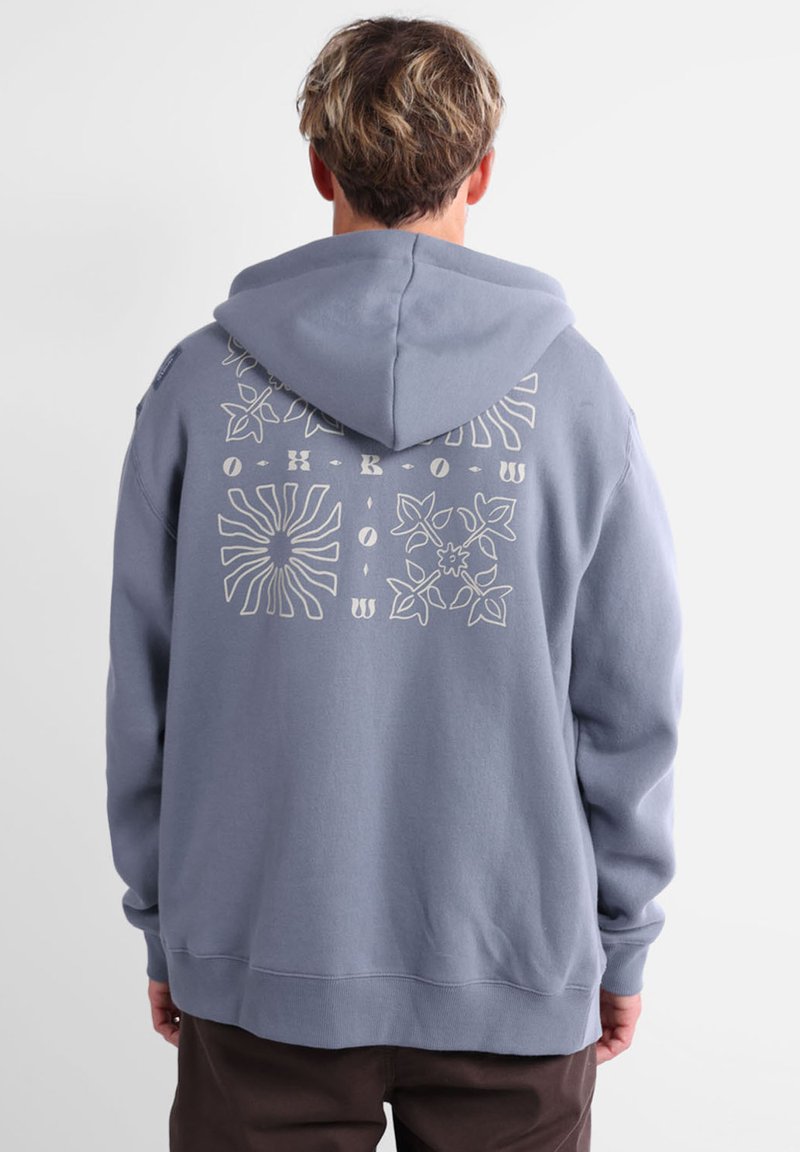 Hoodie bleu clair à coupe décontractée, avec un imprimé graphique au dos incluant des motifs floraux et abstraits en blanc.