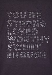 T-shirt nera con testo in argento decorato con borchie che recita "SEI FORTE AMATO VALGO SUFFICIENTE DOLCE" in diversi caratteri e dimensioni.