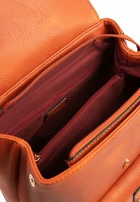 Oranje leren handtas met een textuurafwerking. Heeft een bordeauxrood interieur met meerdere compartimenten en ritssluitingen.