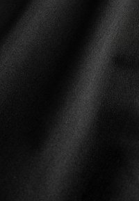 Čierna textúrovaná látka s hladkým povrchom a viditeľným rebrovaním. Záhyby a ohyby vytvárajú rôzne hĺbky a odrazy svetla.