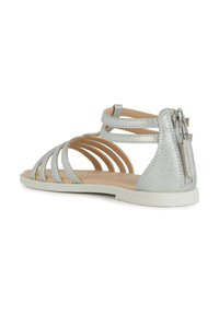 Sandalias gladiador plateadas con múltiples tiras delgadas y un reverso texturizado. Presentan un cierre de cremallera y una suela plana blanca.