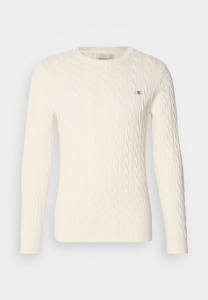 Cable-knit, cream sweater with long sleeves, round neckline, ribbed cuffs and hem, featuring a small logo detail on the chest.