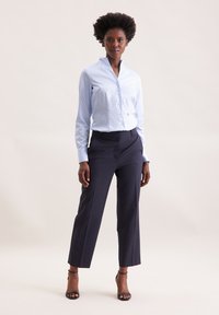 Camicia button-up a righe blu chiaro con colletto alla coreana, abbinata a pantaloni blu navy scuri, caratterizzati da una vestibilità su misura e un taglio sopra la caviglia.