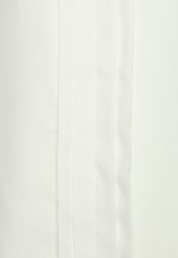 Vit tyg med vertikala veck som löper ner längs mitten, med en slät textur och lätt glans. Minimalistisk design.