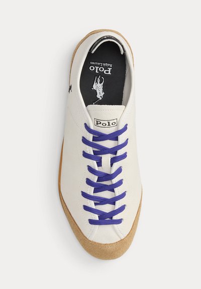 Baskets blanches Polo Ralph Lauren avec lacets violets, bout en daim beige et semelle intérieure noire avec logo Polo et motif cavalier.