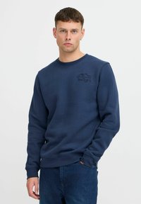 Felpa blu navy realizzata in morbido tessuto, con collo a girocollo e logo testurizzato "ENJOY" con design di montagna sul petto.