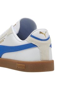 Zapatillas PUMA con parte superior de cuero sintético blanco, raya lateral azul, acento en el talón de ante beige y suela de goma. Logotipo dorado en el talón.