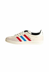 Fehér bőr Adidas Gazelle sneakers piros, kék és fehér csíkokkal az oldalán. Fűzős eleje és klasszikus gumi talpa van.