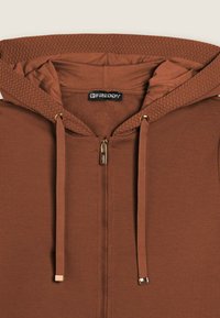 Haut à capuche zippé marron en tissu doux, doté d'une capuche texturée, d'une fermeture éclair dorée et de cordons assortis avec des accents métalliques.