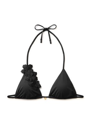 Top bikini triangolare nero con laccio al collo e applicazioni floreali sulla coppa sinistra, con un piccolo charm dorato al centro.