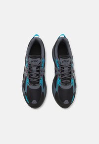 Sapatos de atletismo cinzentos com detalhes em azul, apresentando um cabedal em malha, ponta reforçada e sistema de atilhos tradicional. Textura suave, design leve.