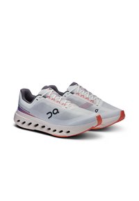 Baskets de sport blanches avec une tige en mesh, des accents violets et une semelle texturée. Présentent un bout arrondi et un design de coussinage prononcé.
