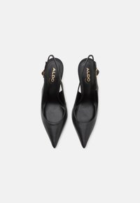 Escarpins slingback en cuir noir avec bouts pointus, dotés de brides réglables et d'une boucle dorée, mettant en avant une texture lisse.