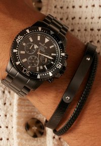 Schwarze Chronographuhr mit Edelstahlband, runder Zifferblatt, weißen Stundenmarkierungen und kombiniert mit einem schwarzen Leder- und geflochtenen Armband.