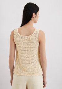 Beige, gebreide mouwloze top met een textuurafwerking en een ronde halslijn, gekenmerkt door een ontspannen pasvorm en zacht, lichtgewicht garen.