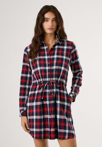 Rood, blauw en wit geruit flanellen jurk met lange mouwen, knoopsluiting, trekkoord in de taille en zijzakken. Zachte textuur.