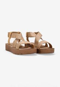 Sandalias marrones con correas trenzadas en tono beige y suela de plataforma. El diseño presenta correas cruzadas y acentos texturizados para mejorar el agarre.