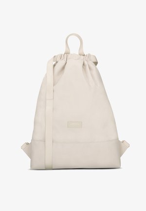 Mochila de cuerdas color beige hecha de tejido suave, con un asa superior, correas ajustables y una base rectangular con un parche de logo.