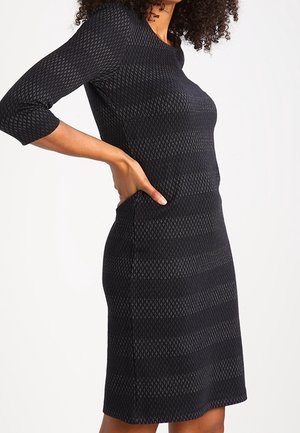 Czarna dzianinowa sukienka z rękawami do połowy przedramienia, z fakturowanym wzorem i dopasowanym krojem sięgającym do połowy uda.