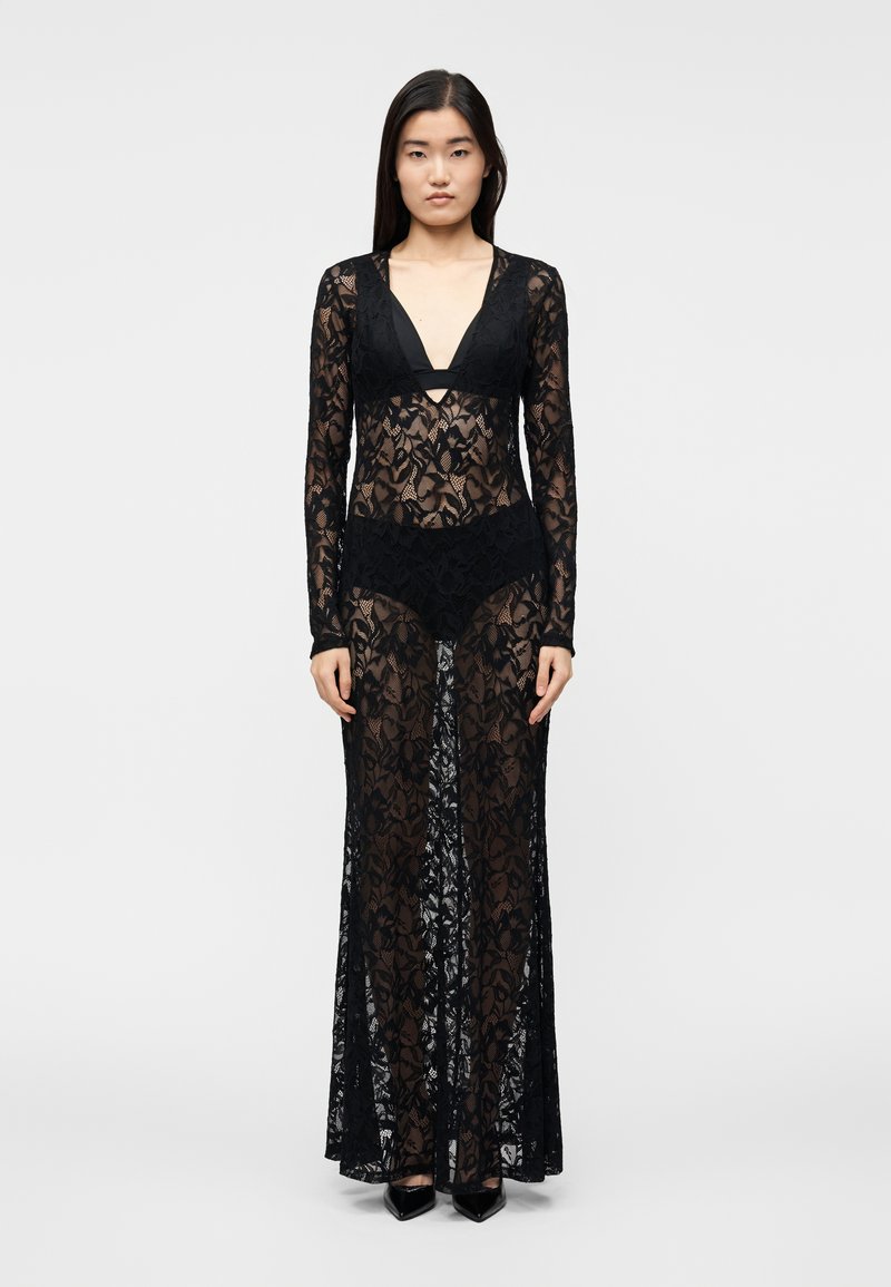 Juoda nėriniuota suknelė su ilgomis rankovėmis, gilia V formos iškirpte, aptempta silueto linija, puošta gėlių raštais ir permatomomis detalėmis visame audinyje.