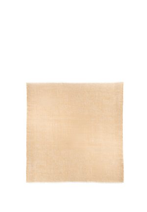 Beżowa kwadratowa chusta z delikatnymi frędzlami na krawędziach i miękką, lekko teksturowaną tkaniną.